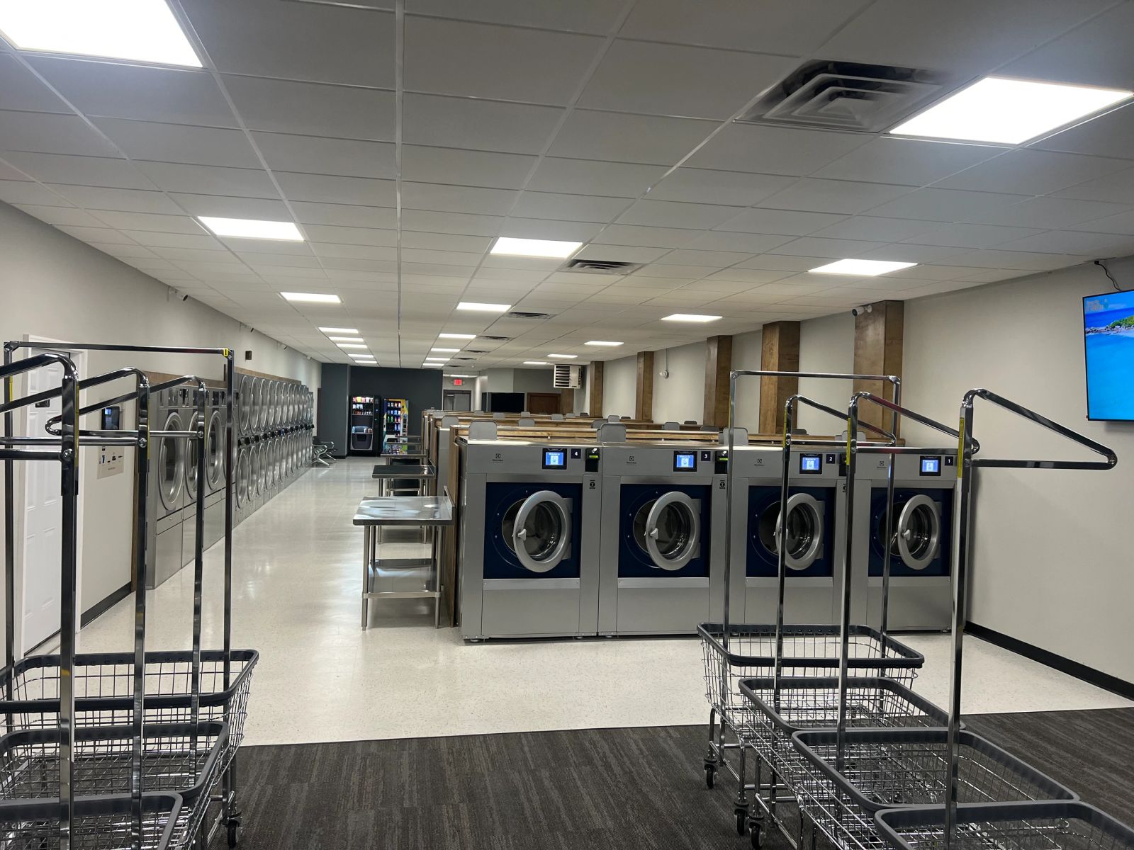 Wide view of the Clean Sheets Laundromat floor with washers, carts and folding tables