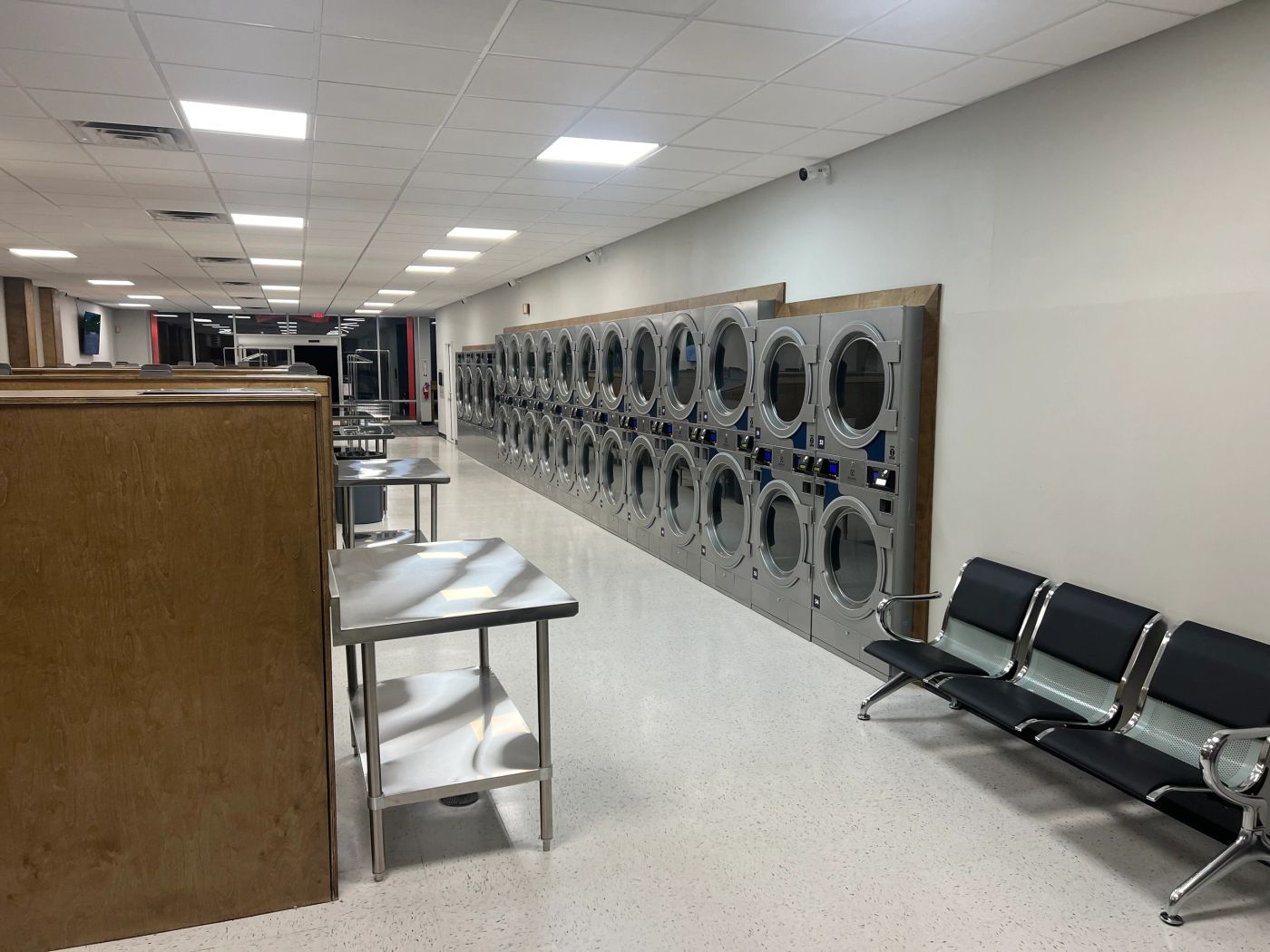 A long wall of stacked dryers and folding counters at Clean Sheets Laundromat